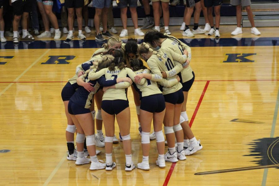 The volleyball team huddles up before a game.