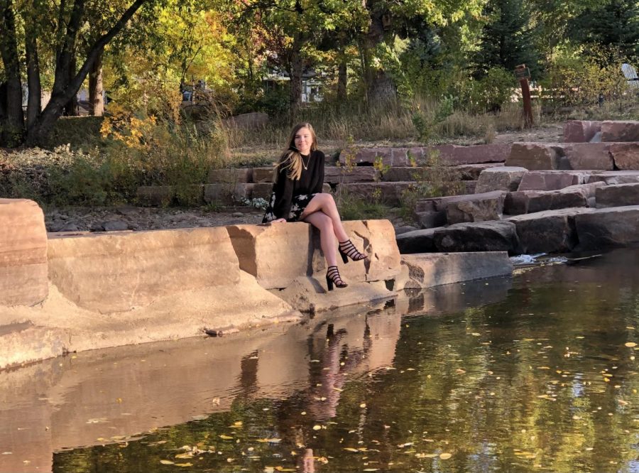 Desiree Wickstrom sits by a lake while posing in Lyons, Colorado for her senior photos taken by her older sister Brittany Gallicchio.