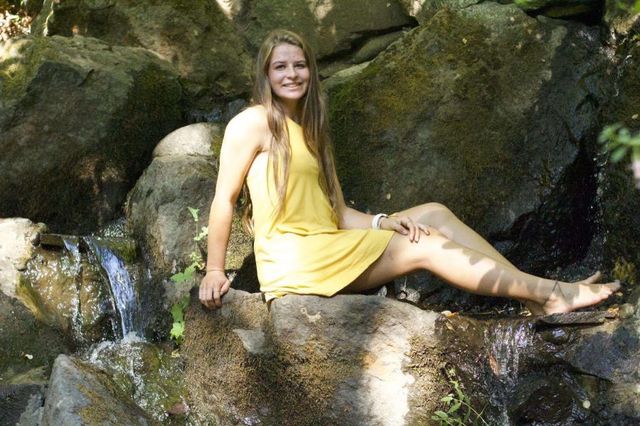 Bella Hewitt smiling for the camera near a waterfall. Most Frederick students know Bella for her amazing work ethic and kindness. 