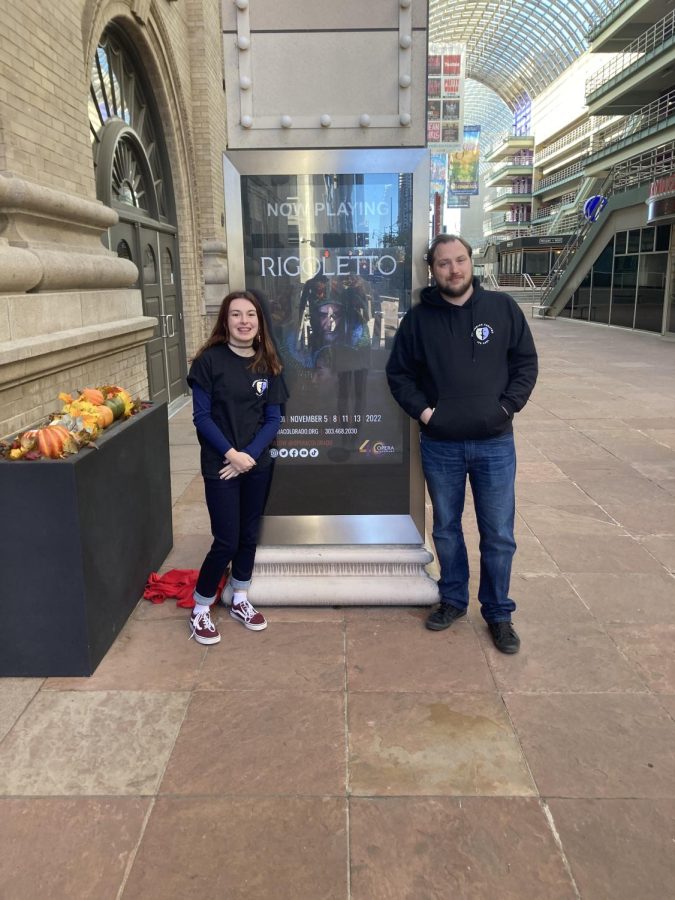 Mr. coon and a student at Frederick standing in front of the Rigoletto poster outside of the Ellie Caulkins Opera House. 