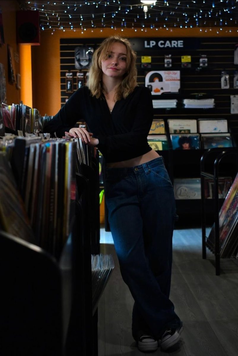 Lily Haas poses in a record store for her friend, who took her senior photos for her. 