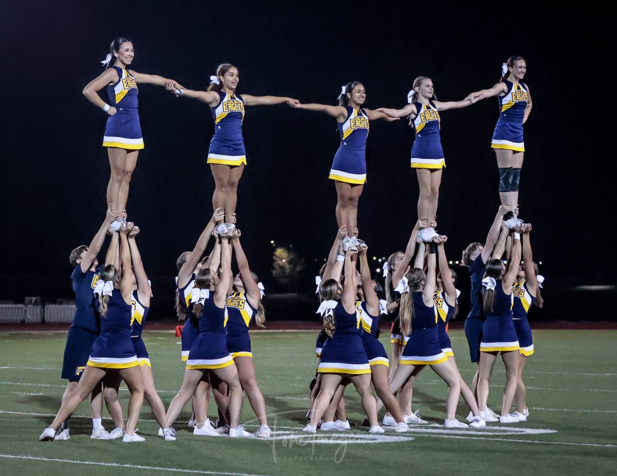 The FHS cheer team performs at halftime during a Frederick football game. With the team becoming co-ed, they are able to complete more difficult stunts and routines. 