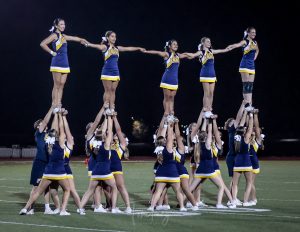 The FHS cheer team performs at halftime during a Frederick football game. With the team becoming co-ed, they are able to complete more difficult stunts and routines. 