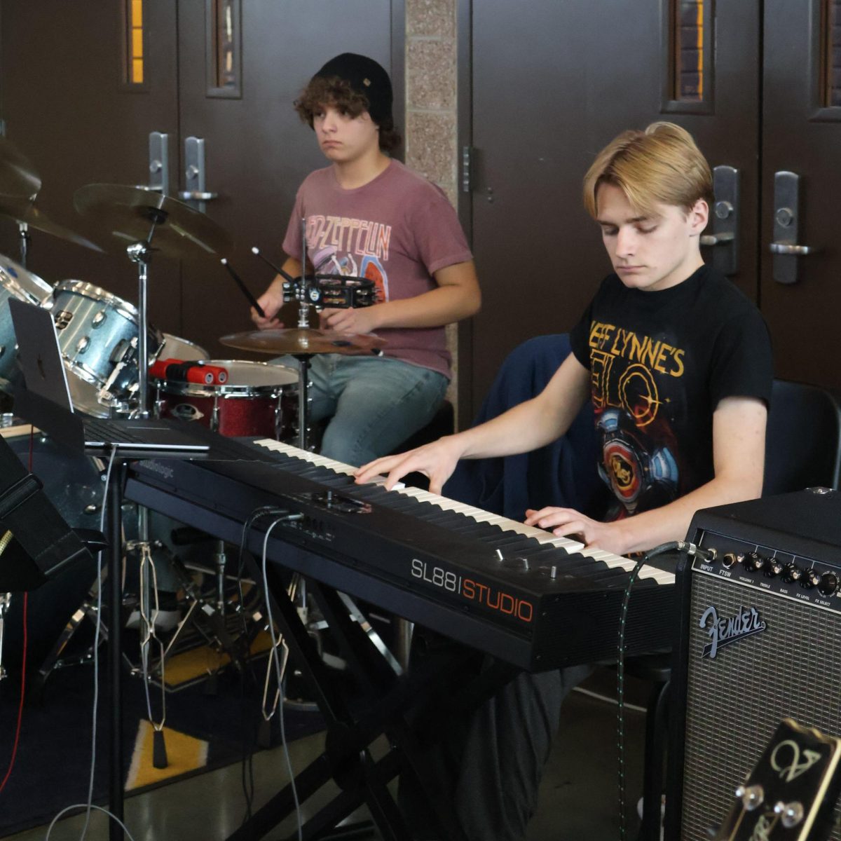 Junior Erik Esqueda-LeRoi keeps time with the drums while senior TJ Mogenson plays the keyboard during the December 10 School of Rock lunch performances. TJ noted that playing in a new place affected how some of his keyboard patches sounded because "the sound you get is a lot different in large spaces like the cafeteria.”