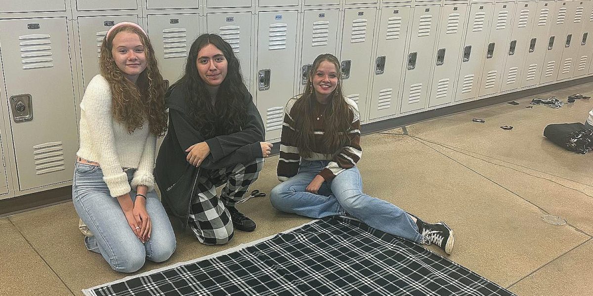 FHS students Maddix Frame, Valerie Madrid, and Peyton Frame sit next to their pieces of fleece before crafting it into a blanket. With three people, a single blanket can take as little as 15 minutes. (Jami Revielle)