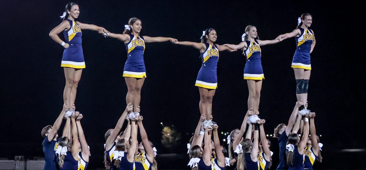 The FHS cheer team performs at halftime during a Frederick football game. With the team becoming co-ed, they are able to complete more difficult stunts and routines. (Courtesy of Christopher Tone)