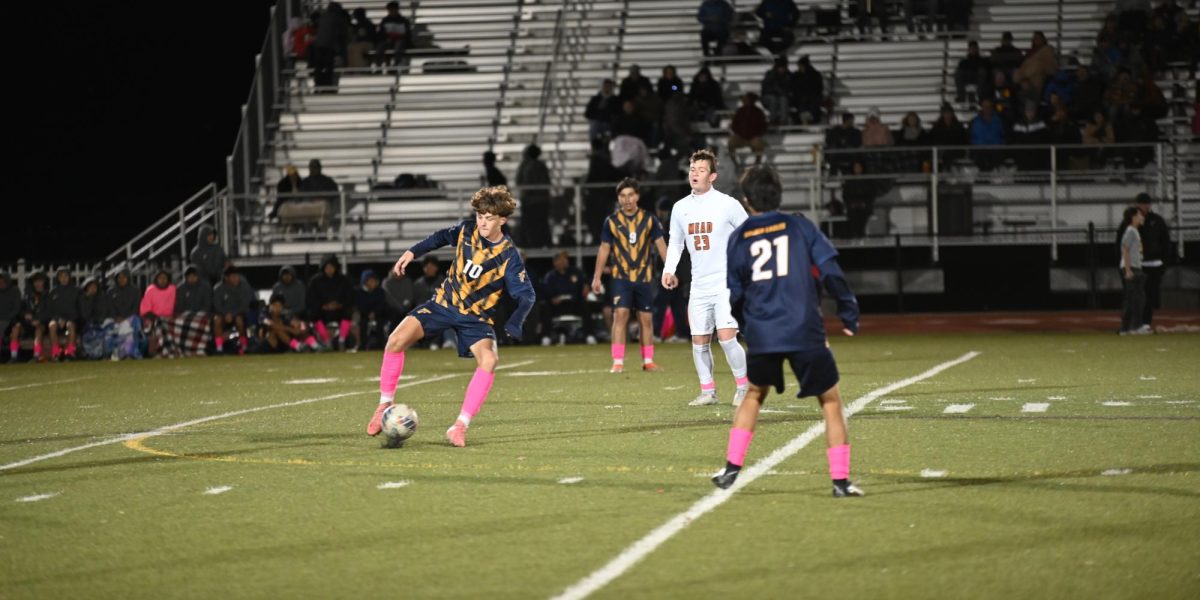 Junior Gavin Coburn dribbles around an opponent during one of the team's games on their home field. The main field at Frederick, used for football, boys and girls soccer, and track is made of turf. Turf is an artificial grass composed of "soft plastic blades of “grass” that come in large sections with a plastic backing made for drainage and the infill, a mixture of rubber pellets and sand that can be made from cork, coconut or plastic” according to AP News.