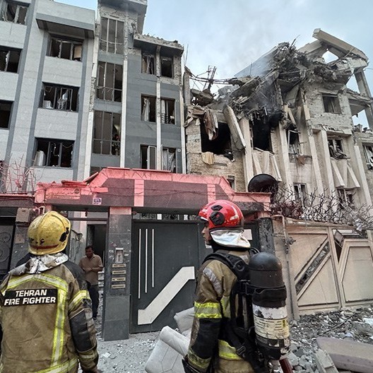 Two Tehrani firefighters asses damage from an Israeli bombing on June 13. After several days of Israel and Iran exchanging fire, the US temporarily ended the conflict by bombing three Iranian nuclear enrichment facilities. (Tasmin News Agency, CC-BY)